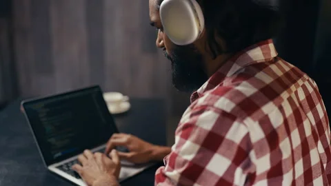 Indian male programmer in headset writing code on laptop, focused on project Video stock 313281669