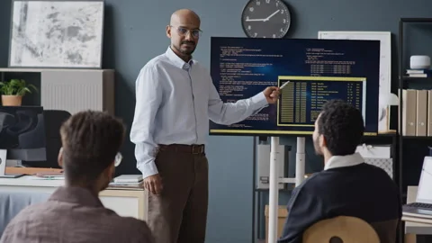 Indian Male Programmer Presenting Code on Screen to Team in Office Vidéo 337483511