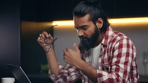 Indian male programmer taking off glasses while working on laptop, eye tension Stock Footage 316836627