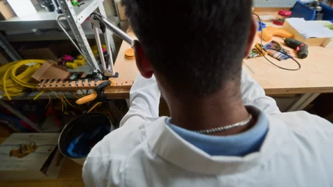 Indian Man Assembling Robot Prototype with Magnifying Glass Stock Footage 343507877