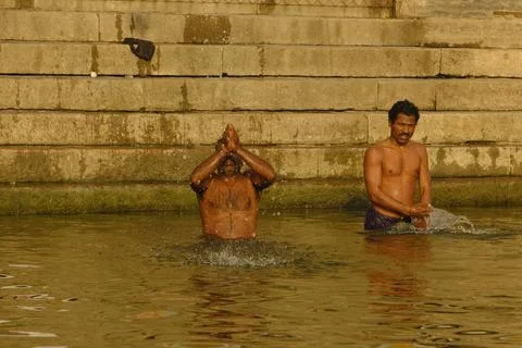 Indian man bathing and making offerings at the Ganges River in Varanasi Stock Photos