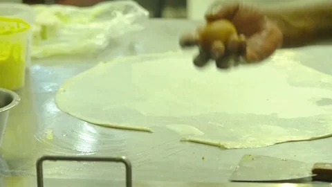 Indian man breaking an egg and pouring on the dough for roti canai at a mamak Stock-Footage 104296828
