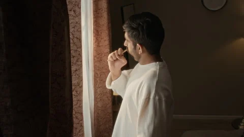 Indian Man Brushing Teeth and Looking out Window in Morning Stock Footage 337715685