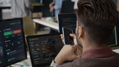 Indian Man Coding on Screens Using Smartphone in Tech Office Stock Footage 337482151
