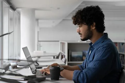 Indian man creative designer working on project using laptop in co-working space Stock Photos