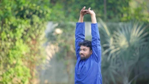 Indian man doing basic yoga pose in a park Video stock 242105460