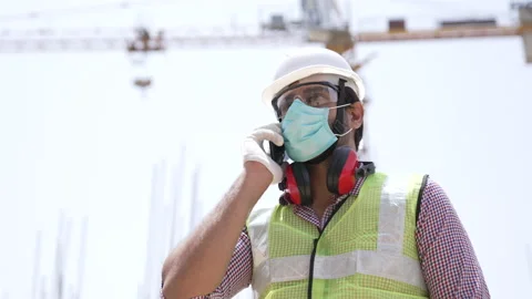 Indian man engineer wearing face mask and hard hat talking on a mobile. Видео 162019086