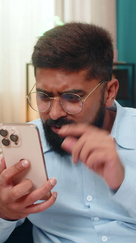 Indian man in glasses squints to read tiny smartphone text brings screen close Stock Footage 313363876