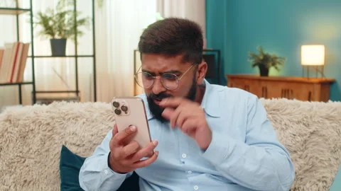 Indian man in glasses squints to read tiny smartphone text brings screen close Stock Footage 314918903