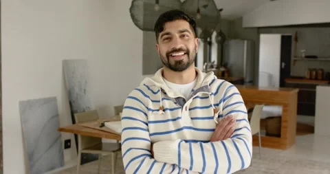 Indian man in hoodie facing camera in kitchen, reacting to camera with smile Stock Footage 341467651