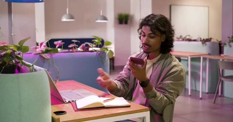 Indian man in jacket receiving phone alert checking it and noting notebook for Stock Footage 340987028
