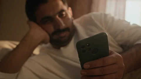 Indian Man Lying in Bed Using Mobile Phone at Night Stock Footage 337714427