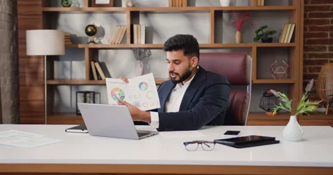 Indian man making online video call chat sitting at modern office talking into Stock Footage 220140599