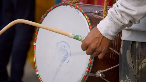 An Indian man playing dhol or drum during a baraat ceremony in an Indian wedding Stock Footage 121780245