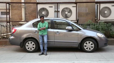 Indian man posing by a modern car in suburban street in Mumbai. Stock Footage 49258668
