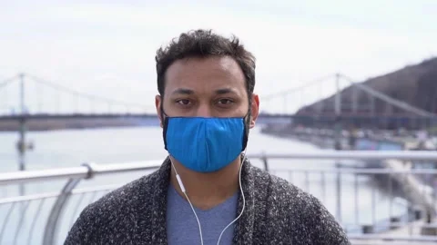 Indian man in protective face mask listening music walking on the street 库存影片 152108731