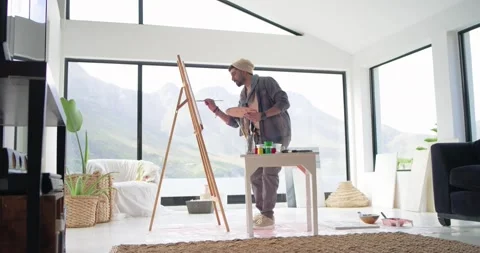 Indian man rising toward easel, mixing paints, painting canvas to create art in Stock Footage 340964524