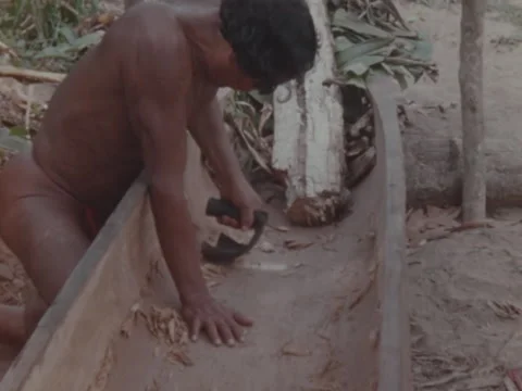 Indian man scoops chips away as he works on new pirogue. Stock Footage 147939399