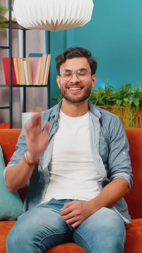Indian man smiling friendly at camera, waving hands gesturing hello, hi Stock Footage 323360392