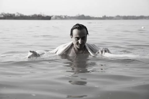 An Indian man taking a holy dip in the river ganges during early morning. h.. Stock Photos