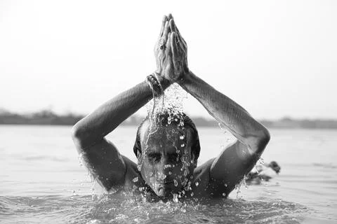 An Indian man taking a holy dip in the river ganges during early morning. h.. Stock Photos
