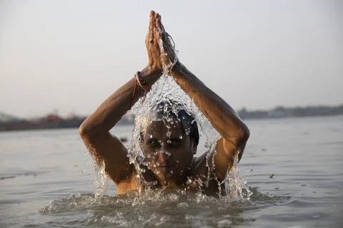 An Indian man taking a holy dip in the river ganges during early morning. h.. Stock Photos