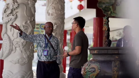 Indian man talking to chinese man seriously at the temple Stock Footage 229777975
