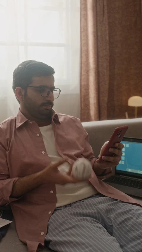 Indian Man Tossing Baseball and Using Smartphone during Remote Work Stock Footage 337720999