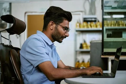 Indian Man Typing on Laptop Computer While Working in Modern Office Stock-Fotos
