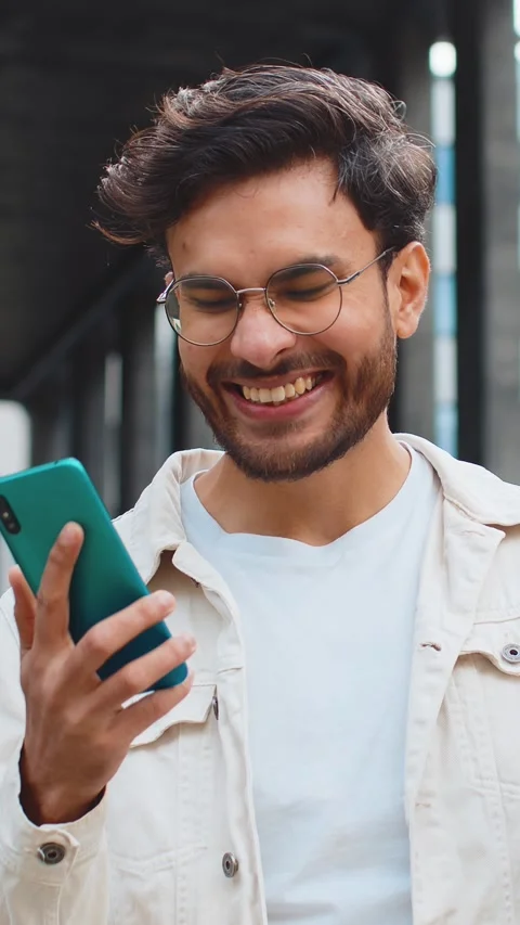 Indian man use mobile smartphone celebrating win good message news outdoors in Stock Footage 323363321