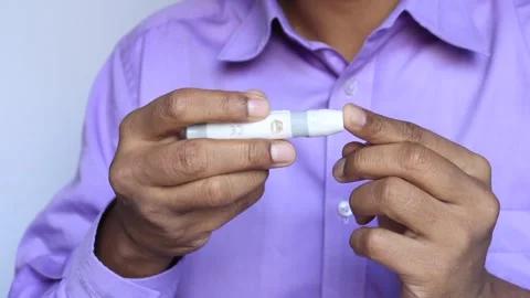 Indian man using blood glucose lancing device for diabetes testing in studi.. Stock Footage 332744630