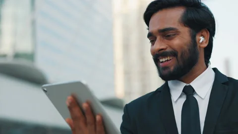 Indian man using digital tablet and earphones for video call Stock Footage 303912652