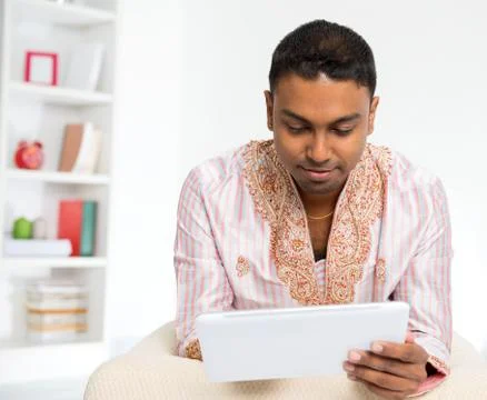 Indian man using digital tablet pc at home. Stock Photos