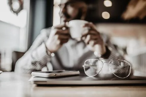 Indian man using laptop computer while drinking a cup hot milk tea, outdoor c Foto stock
