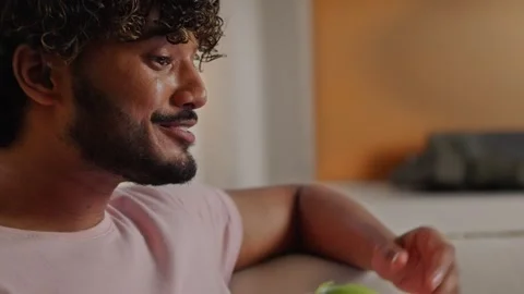 Indian man using laptop when tries green apple. Young guy talking on online Stock Footage 253823306