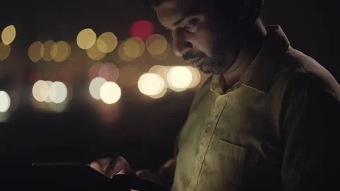 Indian man using mobile phone or tablet in the night outdoors Stock Footage 330885186