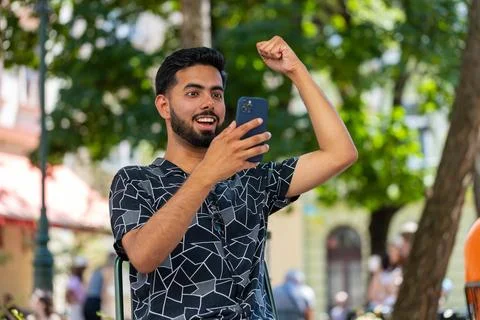 Indian man using mobile smartphone celebrating win good message online news Stock Photos