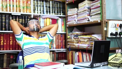 Indian man wearing face shield relaxing and working on laptop in office,4k Stock Footage 138251384