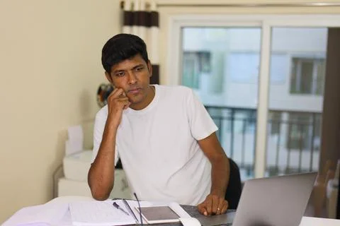 Indian man working on computer laptop at home office desk in deeply thinkin.. Stock Photos