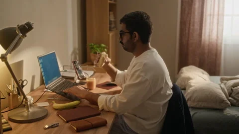 Indian Man Working on Laptop and Having Breakfast at Home Office Stock Footage 337723340