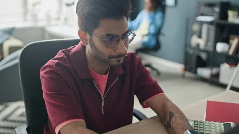 Indian Man Working on Laptop and Taking Notes in Office Stock Footage 338329916