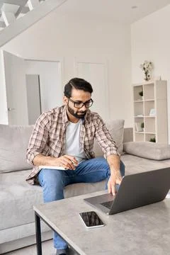 Indian man working or learning online from home office using laptop computer. Stock Photos