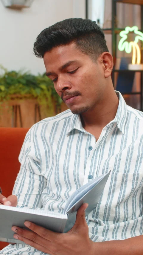 Indian man writes notes in notebook plans day sets schedule and goals pen paper Stock Footage 347617007