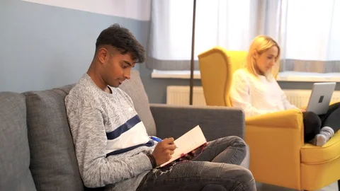 Indian man writing book while girlfriend work at notebook at the background. Stock Footage 119301333