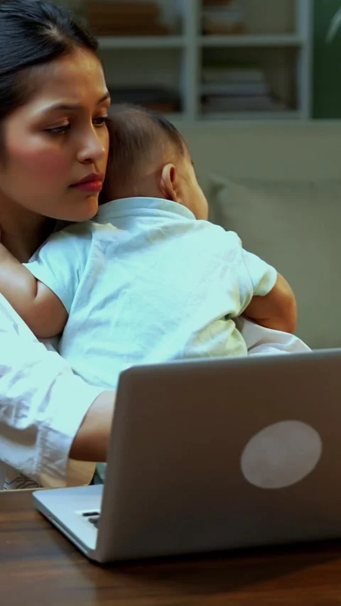Indian mother multitasking with baby working on laptop while father walks Stock Footage 342550873