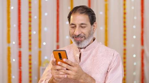 Indian old man using a mobile phone - browsing smartphone. Diwali festival ce... Stock Photos