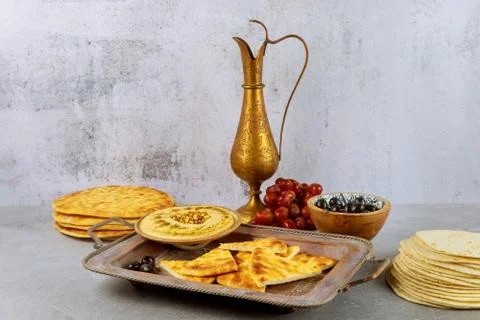 Indian party table with hummus, bread and copper jug. Stock Photos