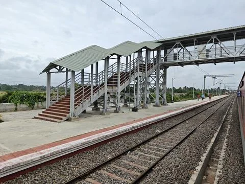 An Indian passenger train stops at a calm rural platform featuring clean tr.. Stock Photos