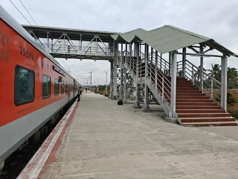 An Indian passenger train stops at a calm rural platform featuring clean tr.. Stock Photos