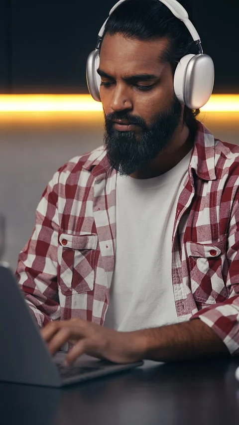 Indian programmer in headset coding on laptop, working remotely from home office Stock Footage 316838244